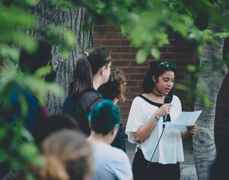 Woman speaking on a microphone outdoors to a group