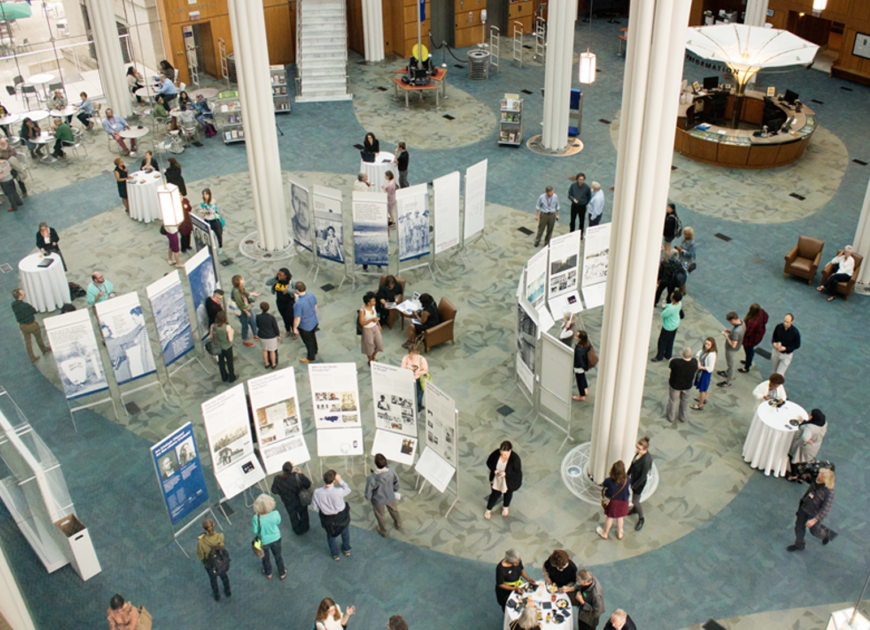 overhead shot of a large room hosting a poster exhibit with people mingling in the room.
