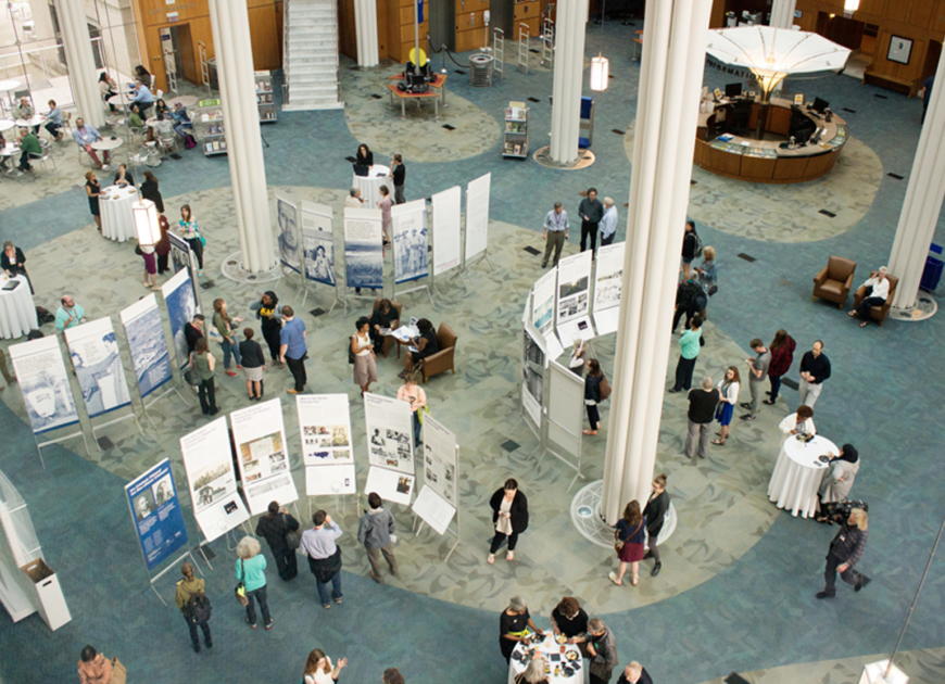overhead shot of a large room hosting a poster exhibit with people mingling in the room.