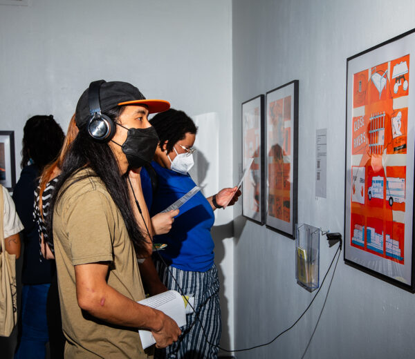 People in an art gallery looking at art and listening to information with headphones.