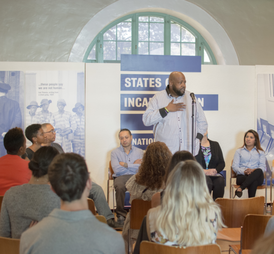 Man standing, speaking to a group of people