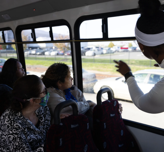 Group of people on a bus, looking out the windows.