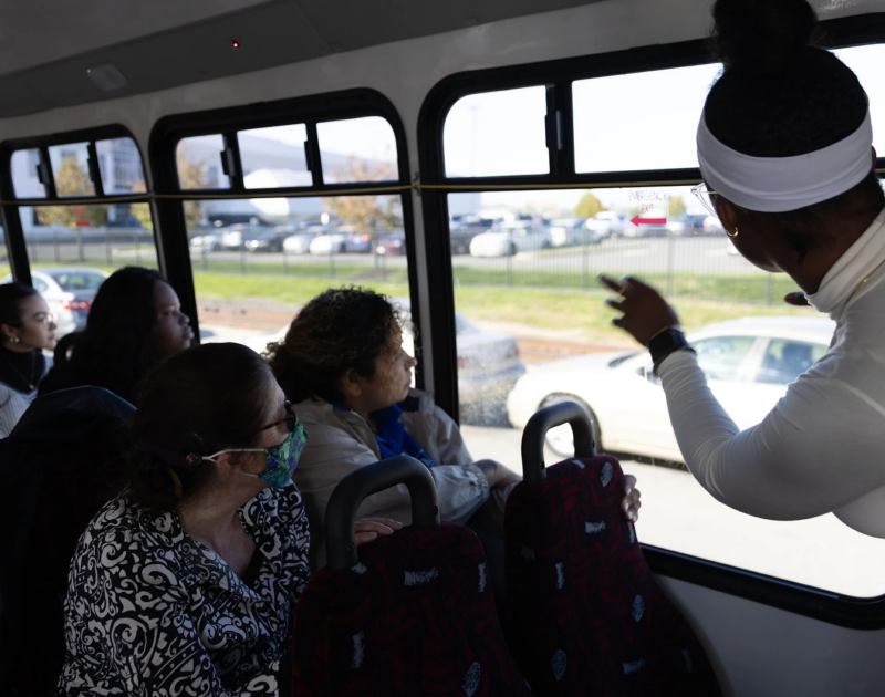 Group of people on a bus, looking out the windows.