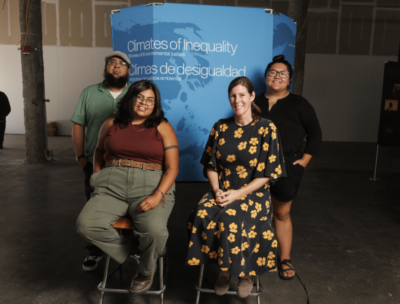 4 people posing in front of a sign