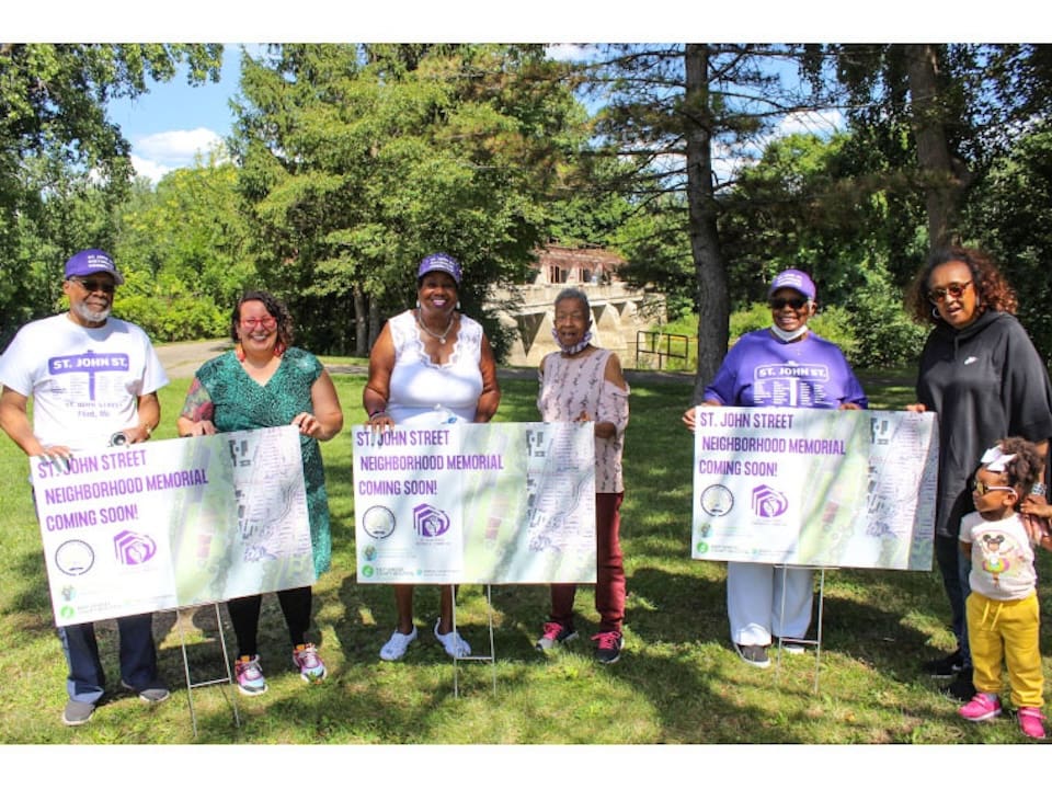 6 adults and one child stand in a park in front of picket signs that read