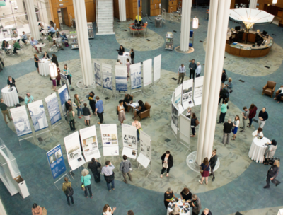 overhead shot of a large room hosting a poster exhibit with people mingling in the room.