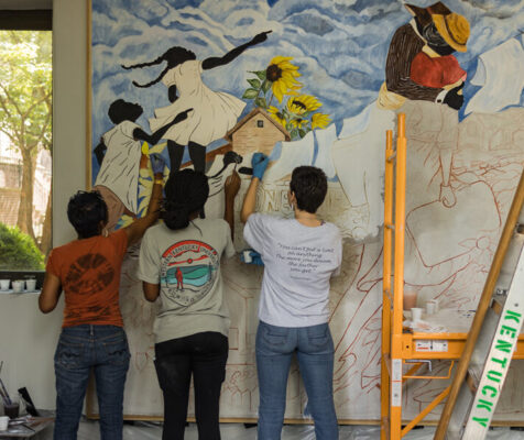 3 artists work on a mural in progress depicting the Jonesville community