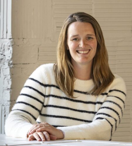 A white woman in her thirties with brown hair and a striped sweater