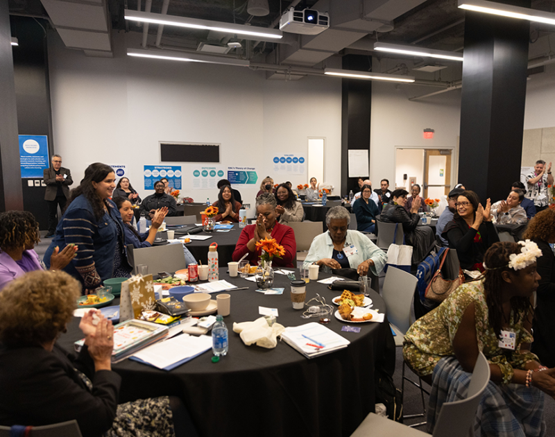 Large group of people gathered around multiple tables.